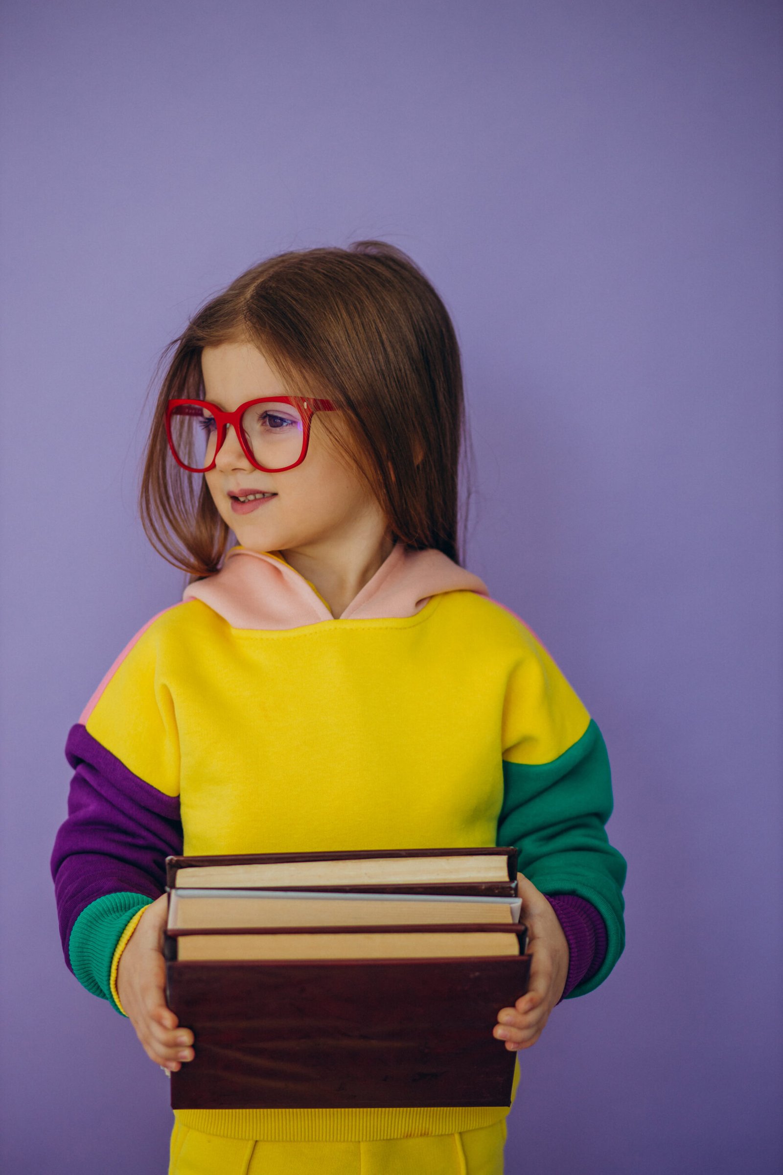 Cute little girl holding books isolated in studio