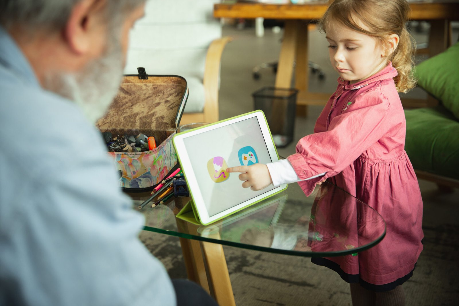 Grandfather and grandchild playing together at home. Happiness, family, relathionship, learning and education concept. Sincere emotions and childhood. Reading books, playing gadgets, look happy.